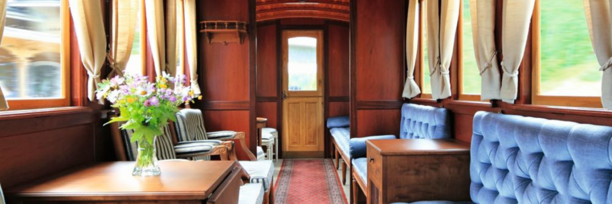 Interior of a sleek, vintage train care with vintage furniture and elegant drapery pulled back from windows.