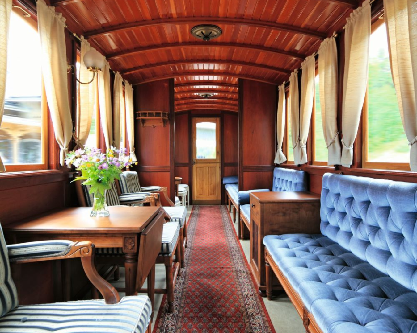 Interior of a sleek, vintage train care with vintage furniture and elegant drapery pulled back from windows.